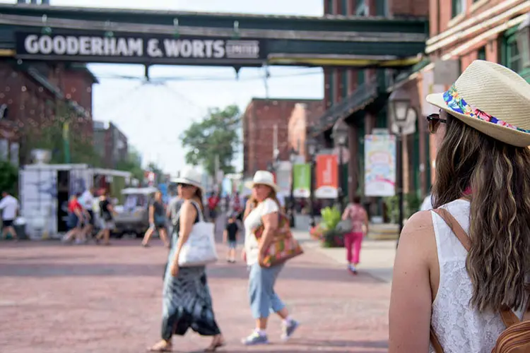 La parte posterior de la cabeza de una mujer mientras se enfrenta a un camino adoquinado mientras otras dos mujeres cruzan.