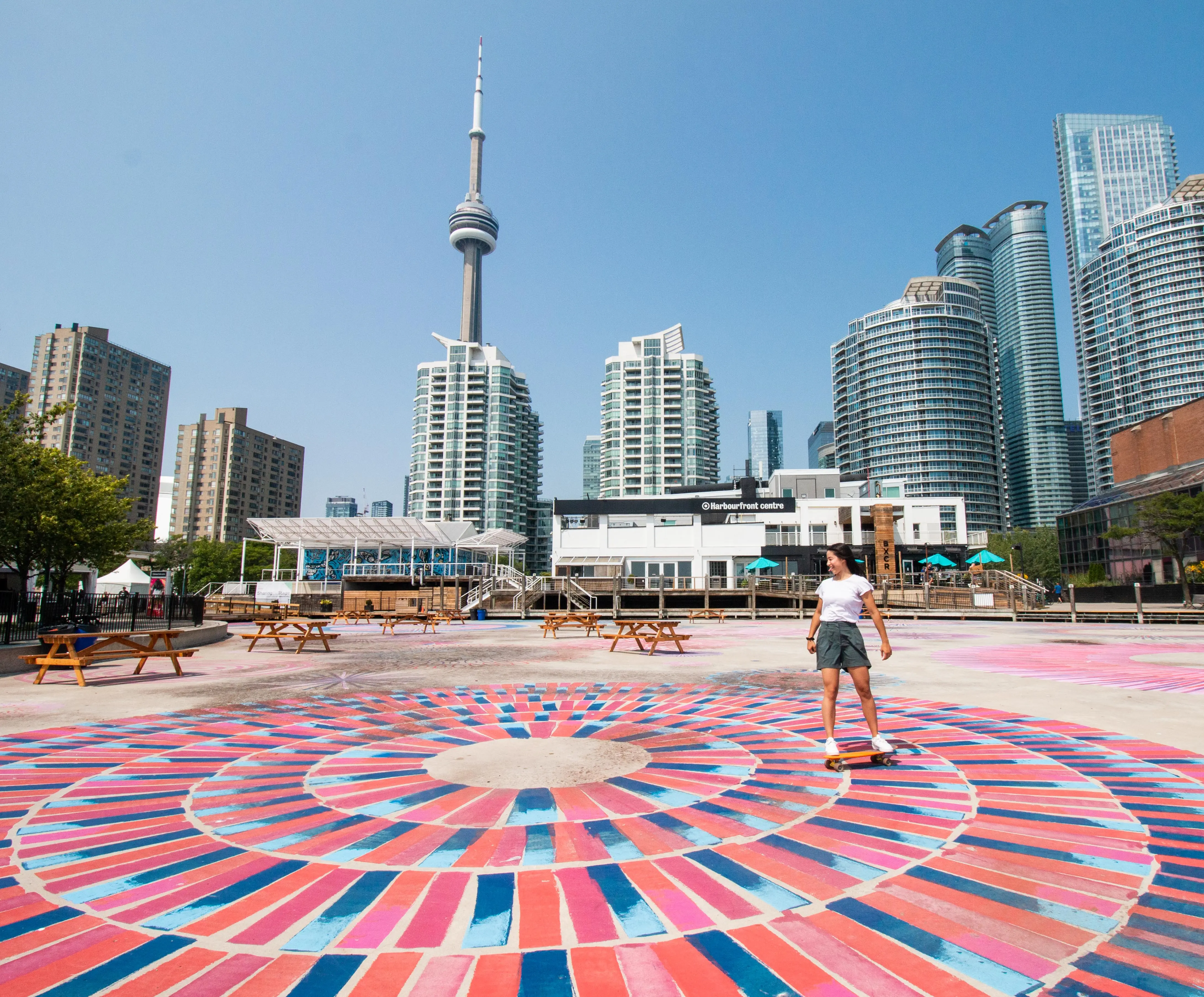 Una persona anda en patineta sobre el colorido pavimento frente al Harbourfront Centre. 