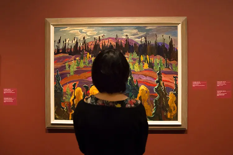 Una mujer se encuentra frente a un cuadro del Grupo de los Siete. 