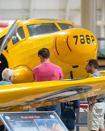 세 사람이 항공 박물관에서 빈티지 항공기를 관람하고 있습니다.