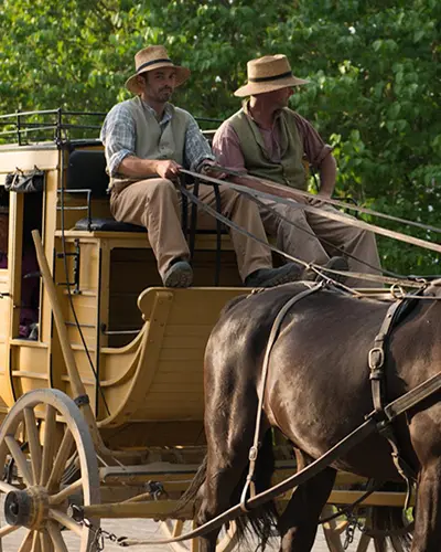 衣装を着たスタッフが再現された 19 世紀の村で馬車に乗ります。