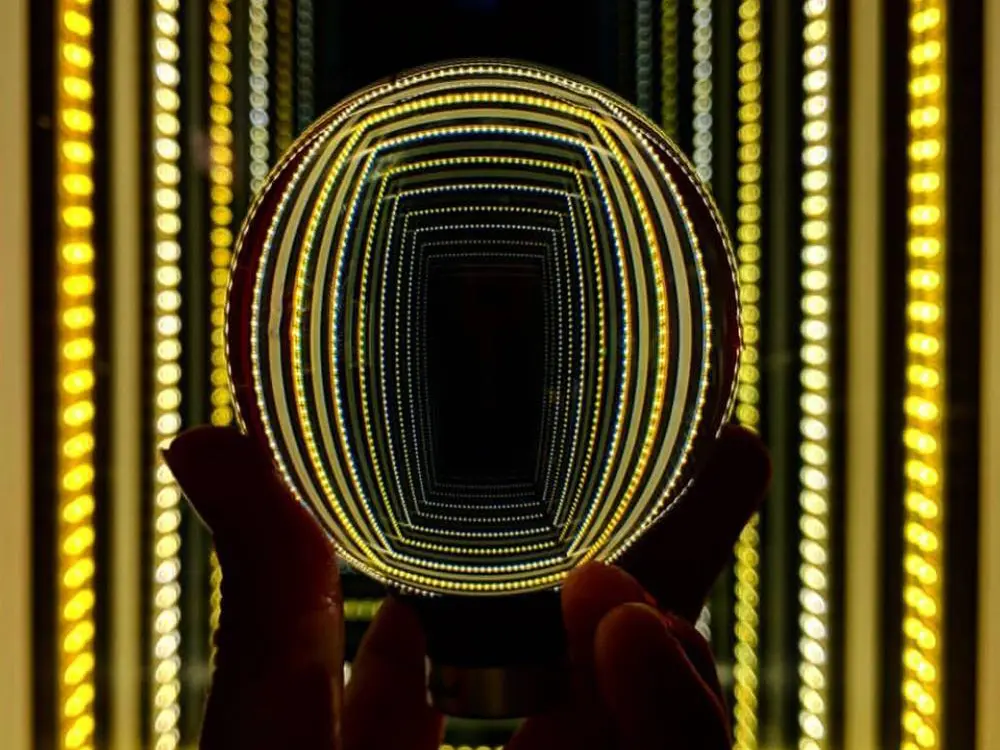 A person’s hand holding up a globe reflecting lights.