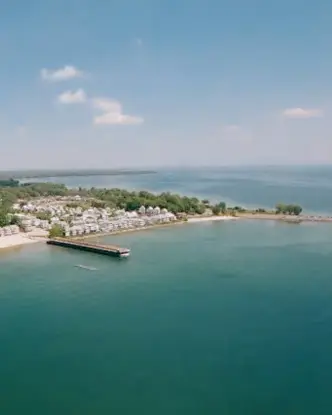  柔らかい青い海、砂浜、明るい空の下の魅力的な海辺の家々が並ぶクリスタル ビーチの航空写真。