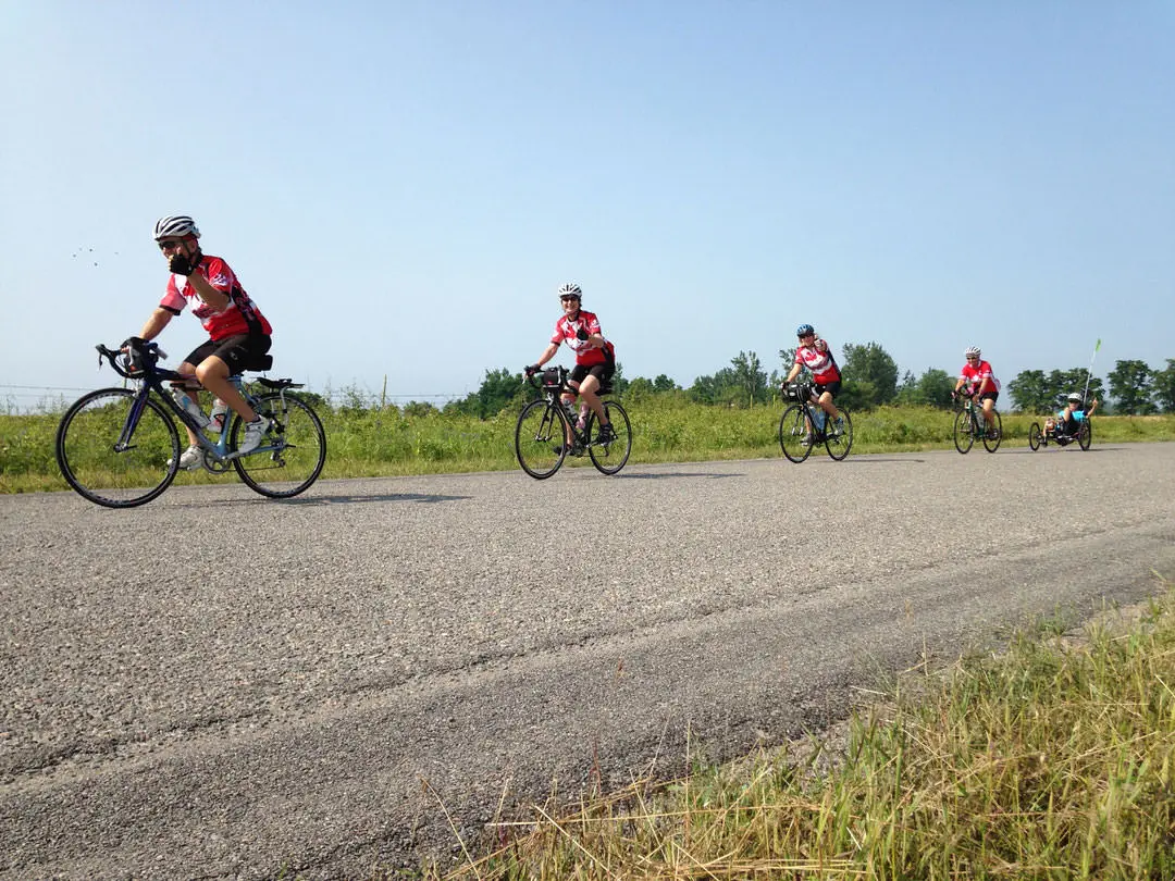 Tres ciclistas montando en un camino rural en un día soleado
