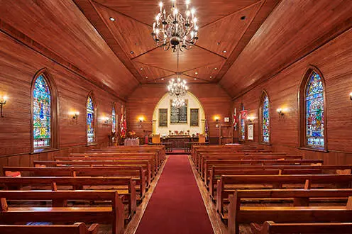 목제 판넬로 덮인 예배당 내부와 양쪽에 3개의 스테인드 글라스 창. 통로는 두 줄의 나무 의자를 분리하고 세 개의 샹들리에가 그 위에 매달려 있습니다.