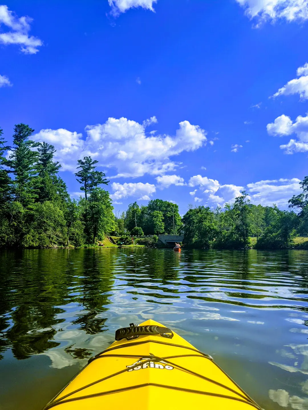 The front of a yellow kayak paddling in a picturesque lake