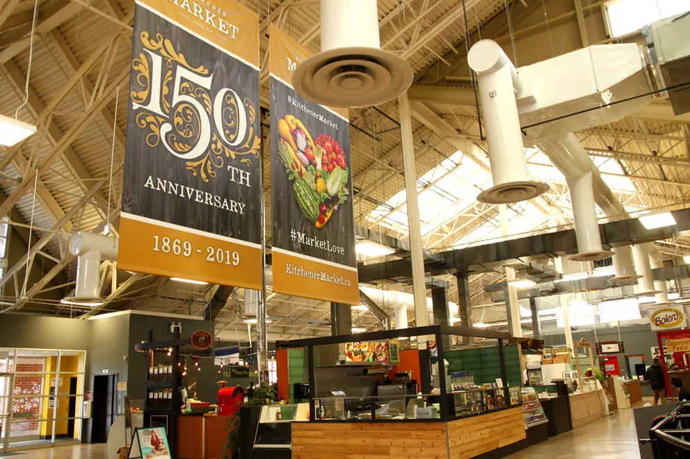 2 banners hanging above extensive array of booths to back wall with one announcing the market’s 150th Anniversary