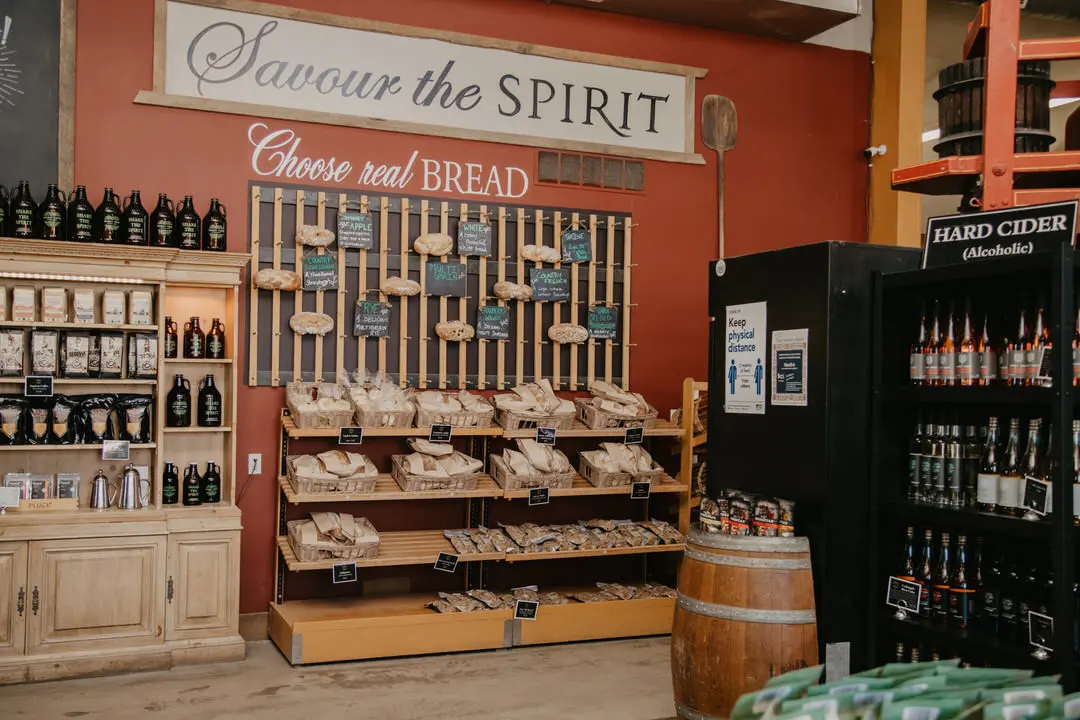 Intérieur d'un magasin du coin avec petit baril à l'avant et étagères sur les deux murs contenant des bouteilles de cidre, du pain fait maison et d'autres bouteilles.