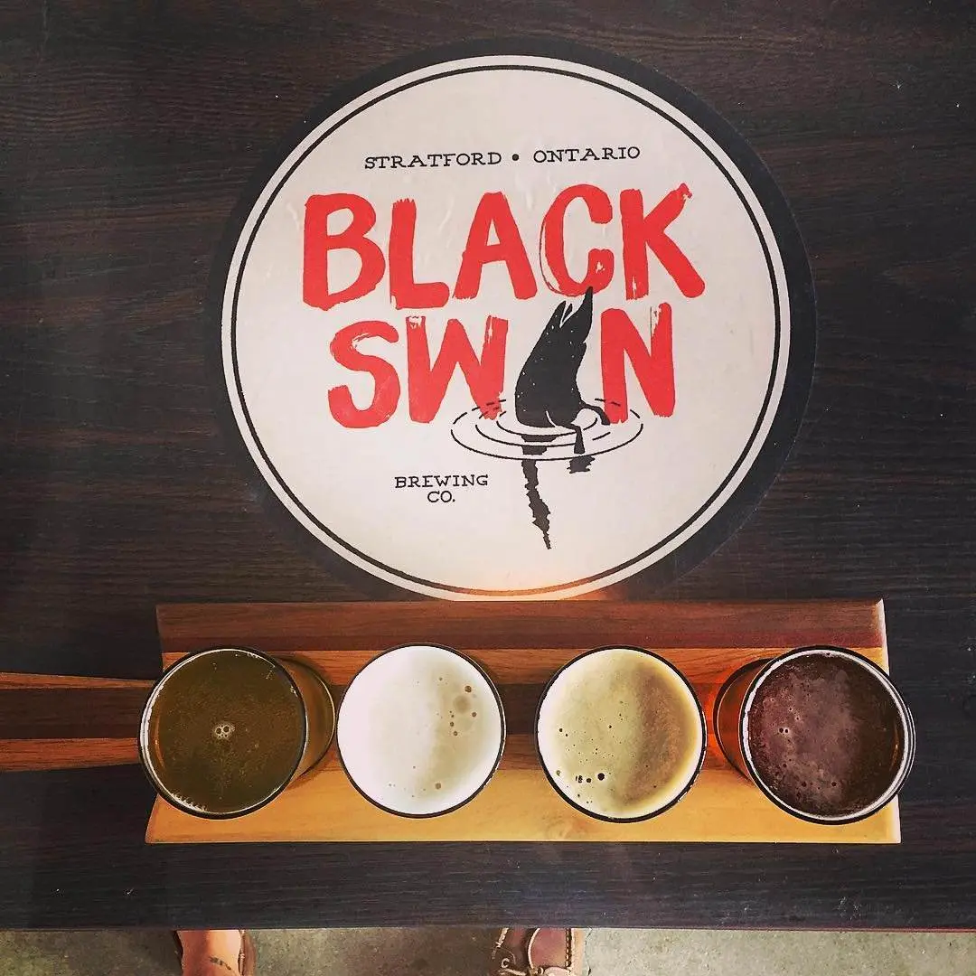 Black Swan 로고 앞의 4가지 다양한 색상의 맥주 비행 오버헤드 샷