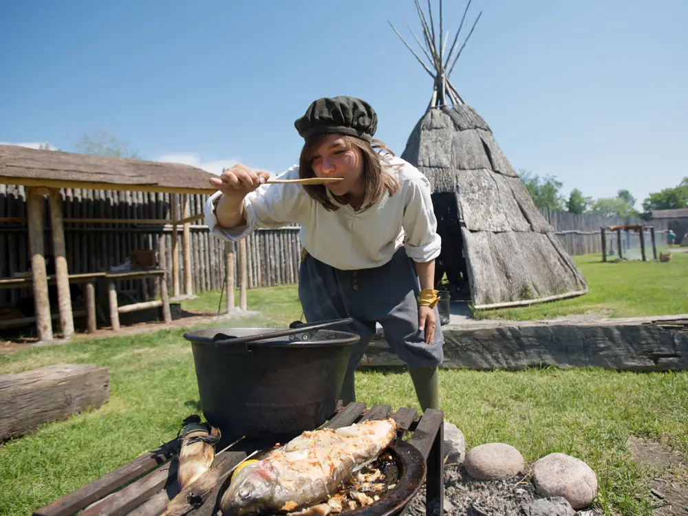 Une personne en costume cuisine sur un feu ouvert