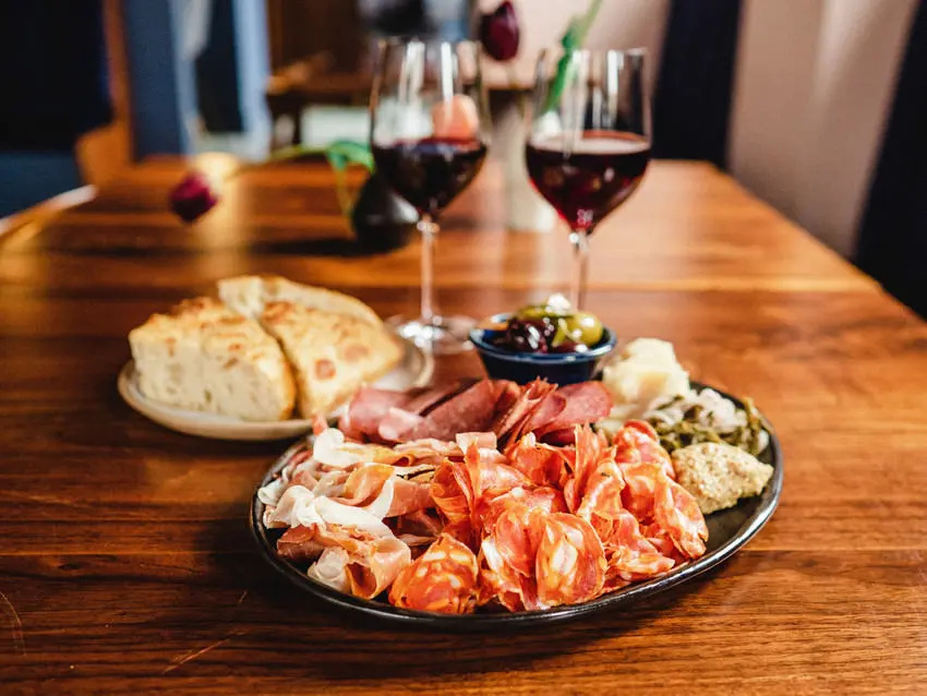 パンのプレートの横にある肉のプレート2杯のワイン