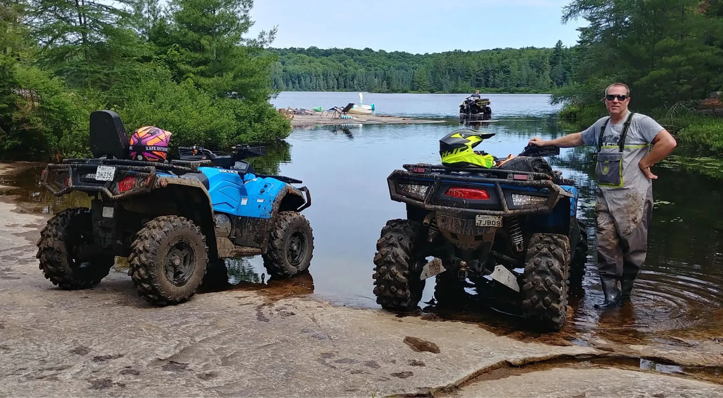 Ein Mann posiert mit zwei langen ATVs am Ufer des Sees