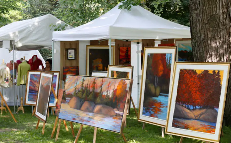 Verschiedene Gemälde umgeben von Bäumen und Zelten