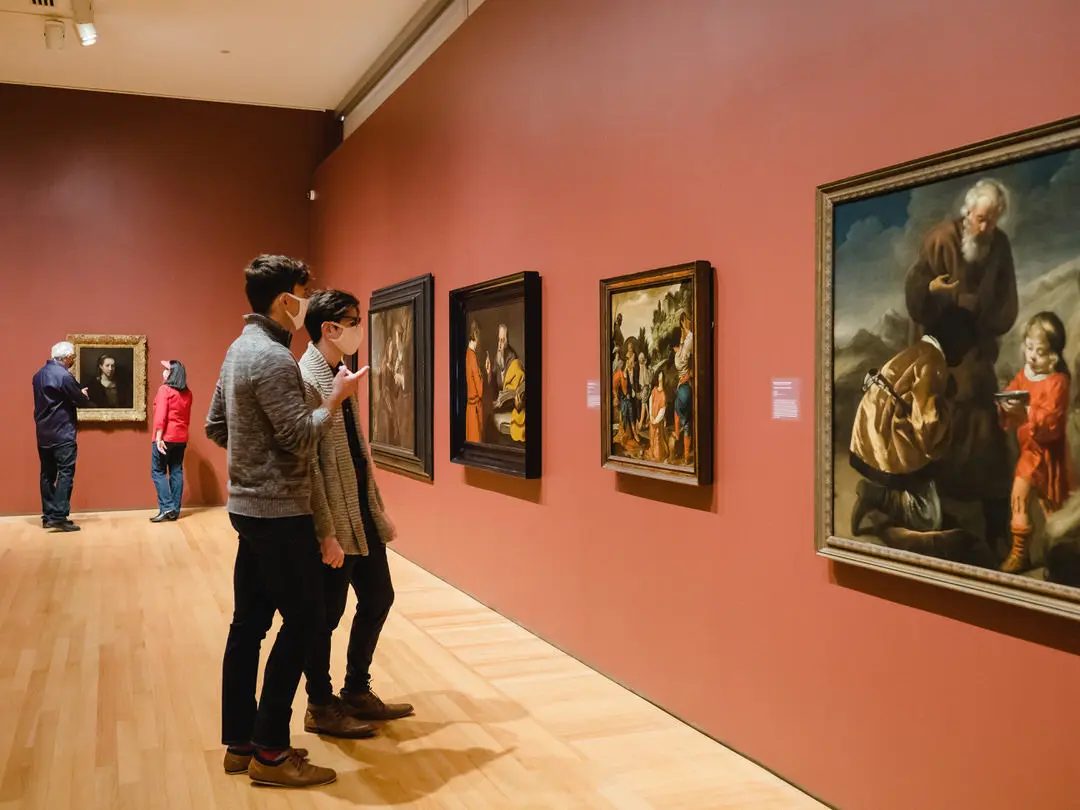 Zuschauergruppen kommentieren angeregt vor Gemälden