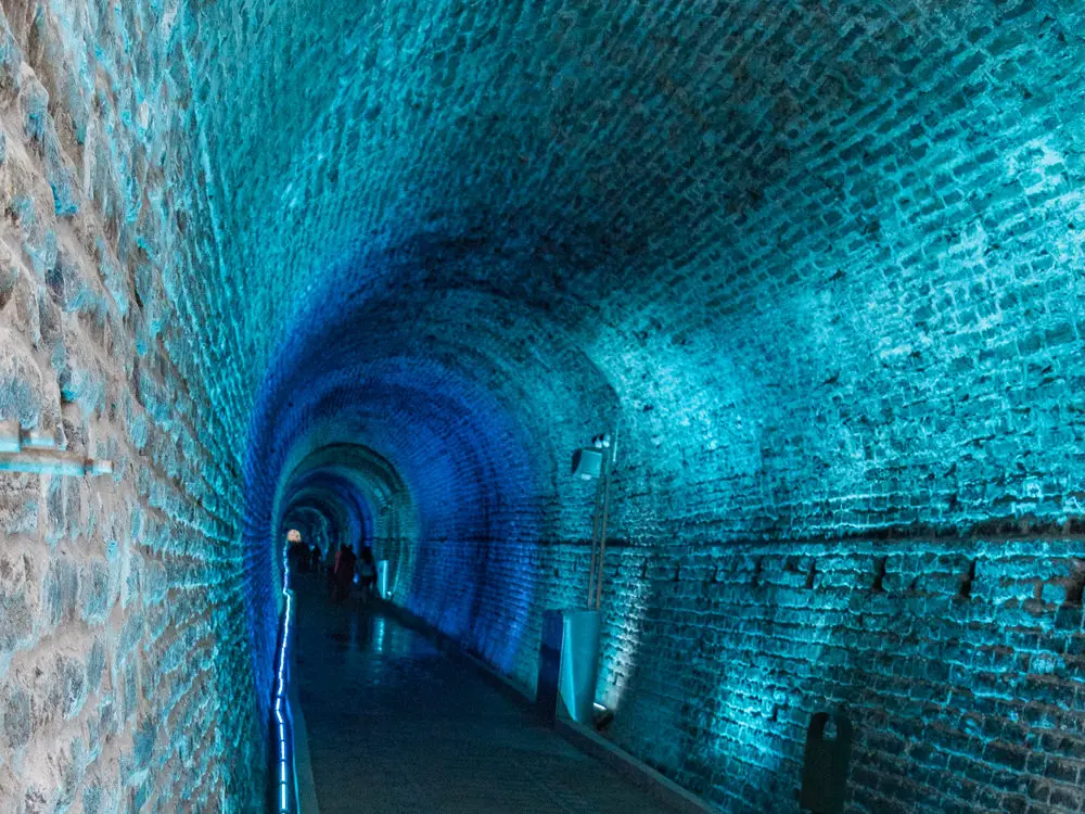 Blue light illuminates a stone tunnel.