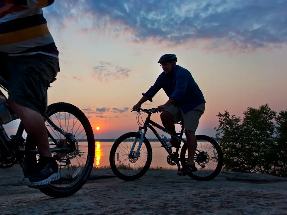 Zwei Radfahrer bewundern den Sonnenuntergang über dem See.
