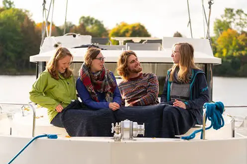 A foursome shares a blanket and a seat in the prow of a boat
