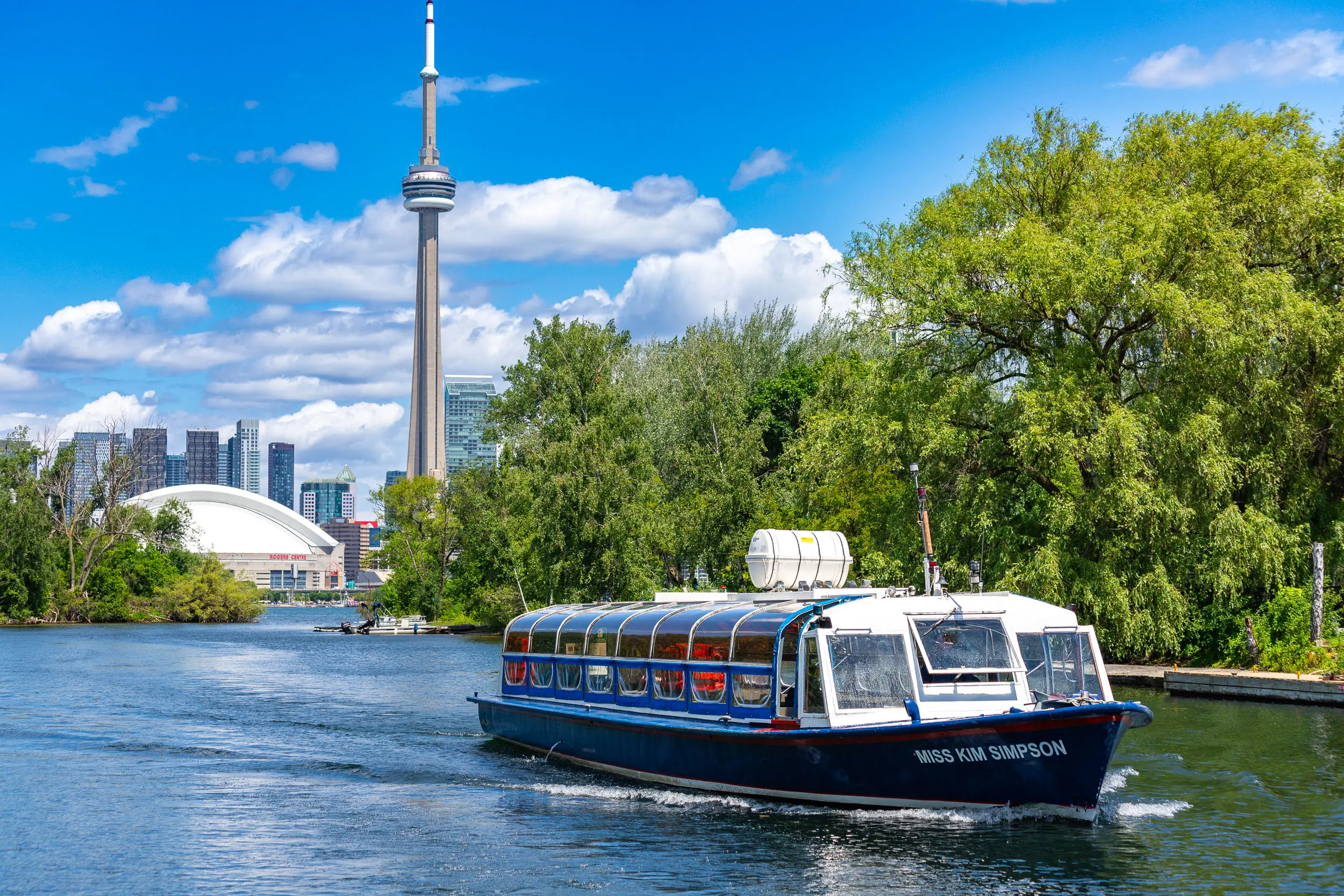Un bateau d'excursion naviguant dans le port de Toronto avec vue sur la tour CN.