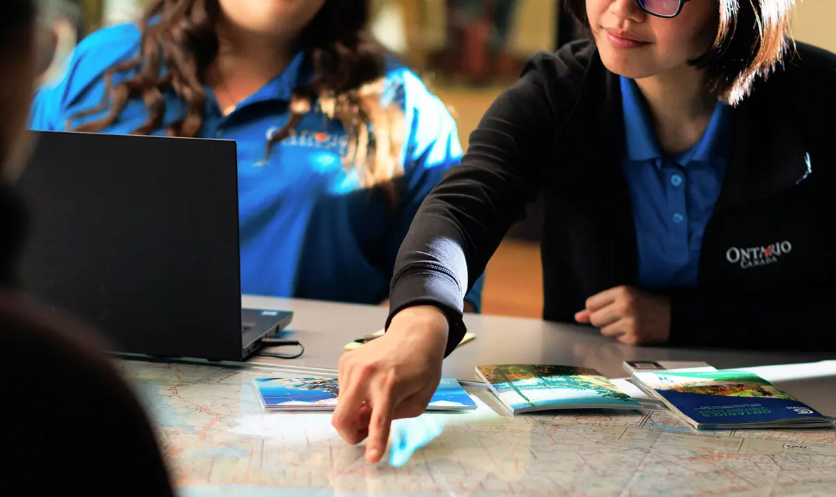 Conseillère en voyages de l’Ontario en uniforme montrant une carte de l’Ontario.