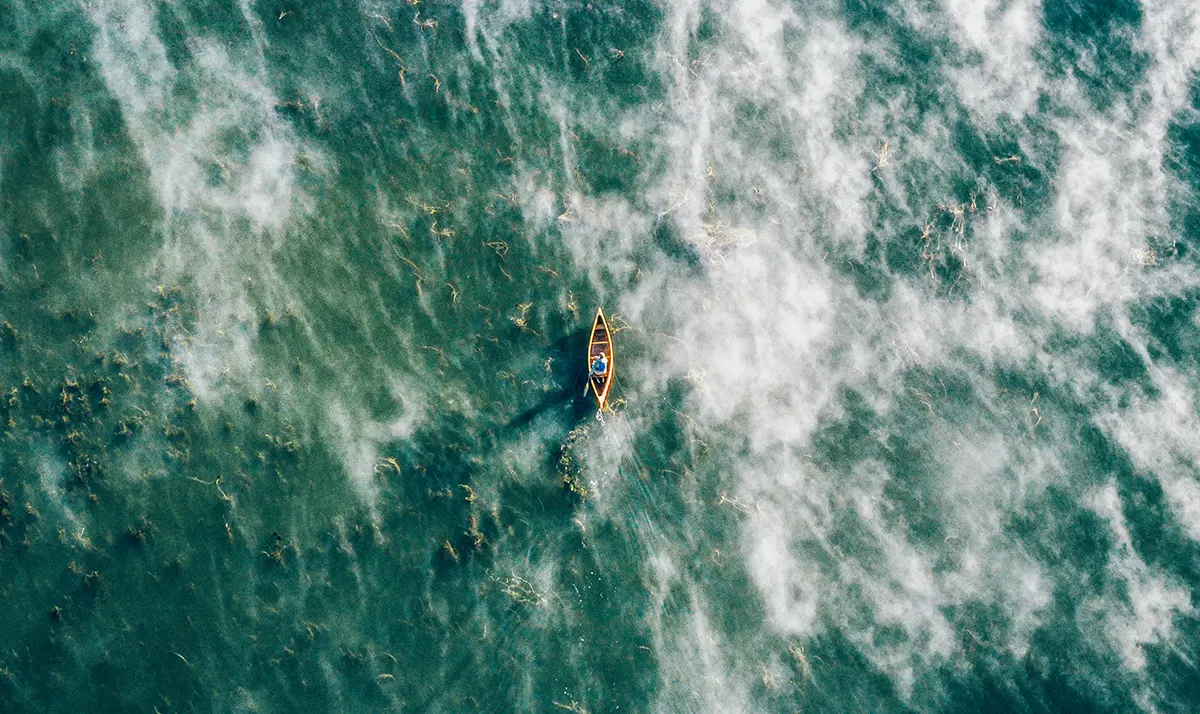 Photo aérienne d’une personne en canot naviguant sur les eaux bleu verdâtre de la baie Seeleys.