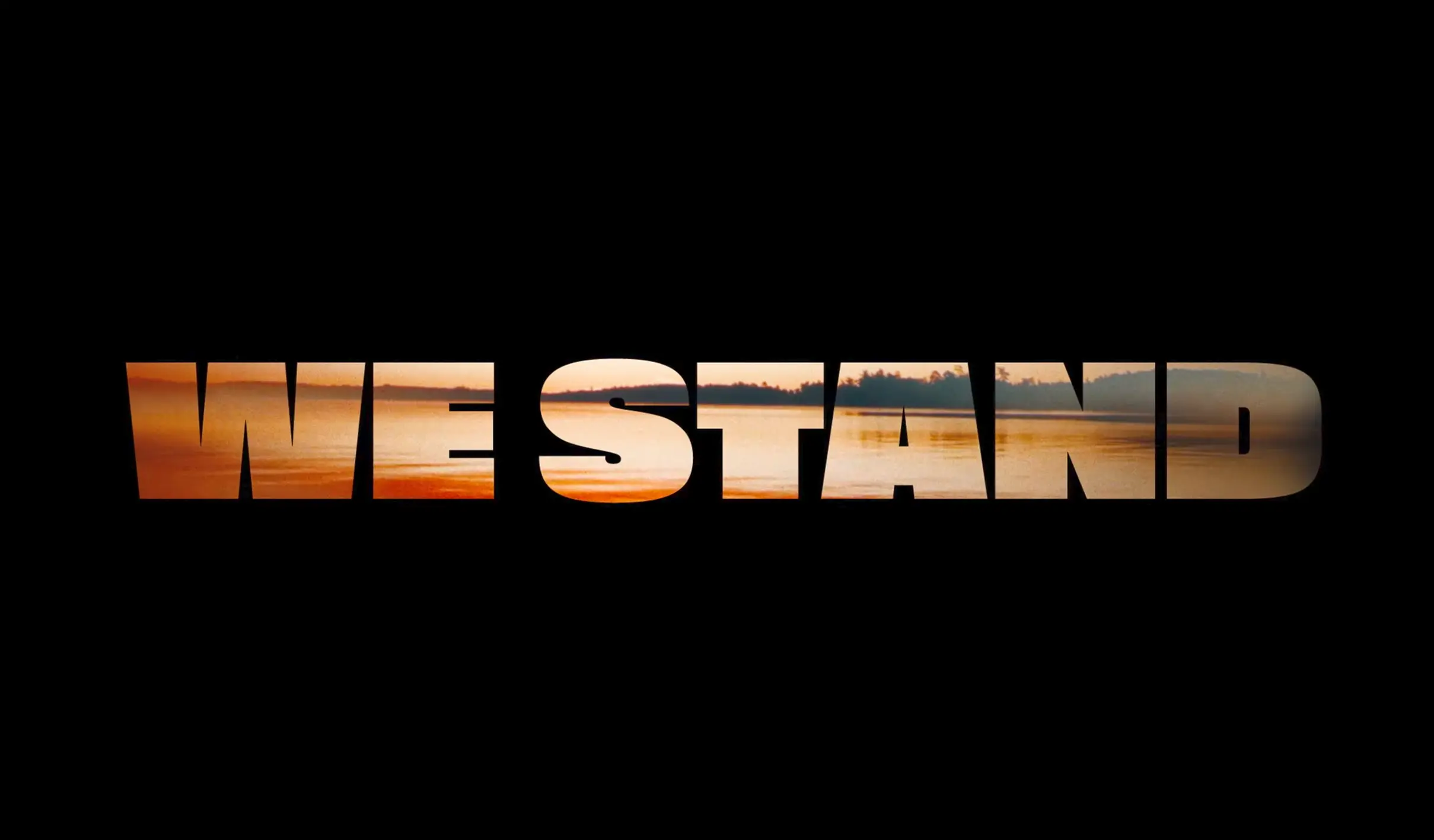 The words "WE STAND" written in a bold font with an amber Ontario lake colouring the letters, over a black background.