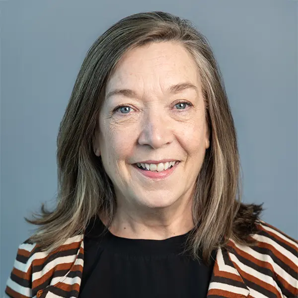 Headshot of Cathy Kirkpatrick, smiling and wearing a black shirt and striped jacket.
