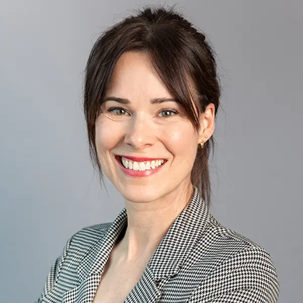 Portrait de Kate Vrancart, souriant et portant un blazer gris.
