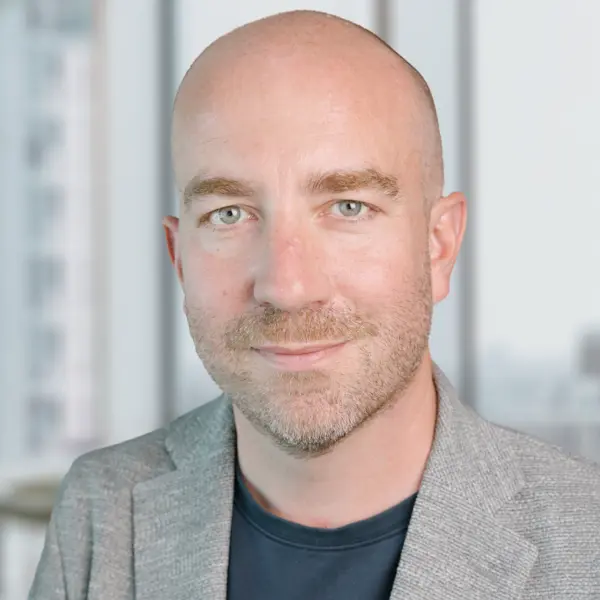 Portrait de Dennis Matthews, souriant et portant un costume.