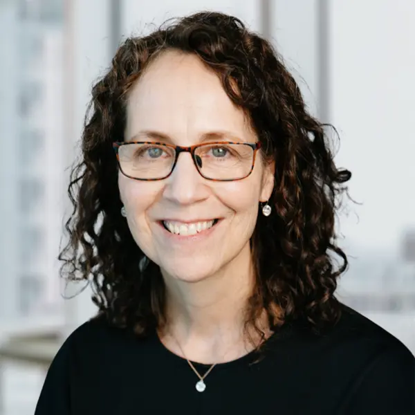 Portrait de Garlene Kubisheskie, souriant et portant un chemisier noir.