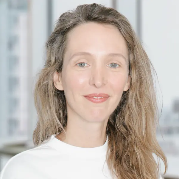 Portrait de Jennifer Stubbs, souriant et portant un chemisier blanc à manches longues.