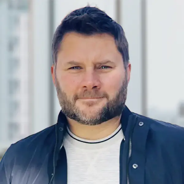 Portrait de Jesse Hamilton, vêtu d’un manteau d’automne, le regard pensif.