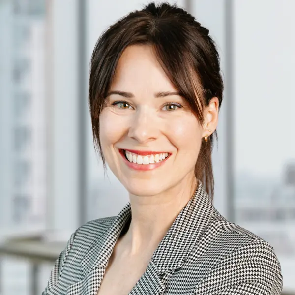 Portrait de Kate Vrancart, souriant et portant un blazer gris.
