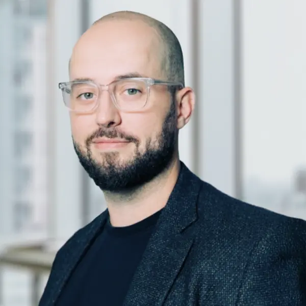 Portrait de Lauchlan Rogers, souriant et portant un blazer foncé.
