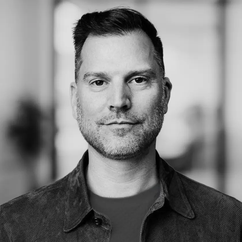 Portrait en noir et blanc de Mark Montefiore, vêtu d’une veste foncée et d’une chemise blanche.