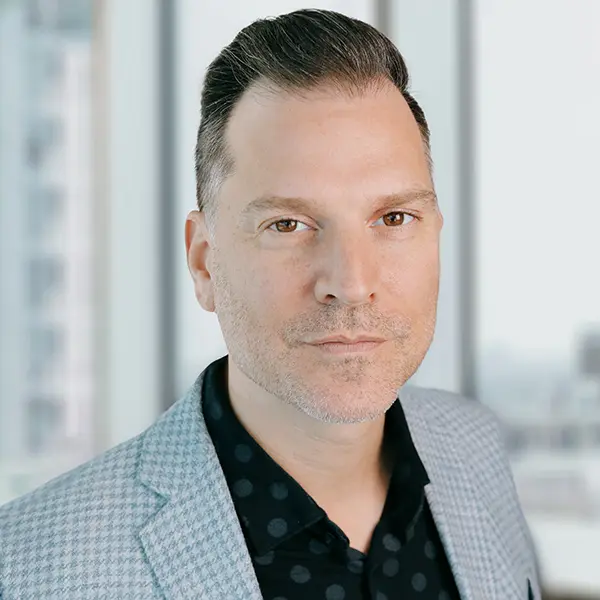 Portrait en noir et blanc de Mark Montefiore, vêtu d’une veste foncée et d’une chemise blanche.