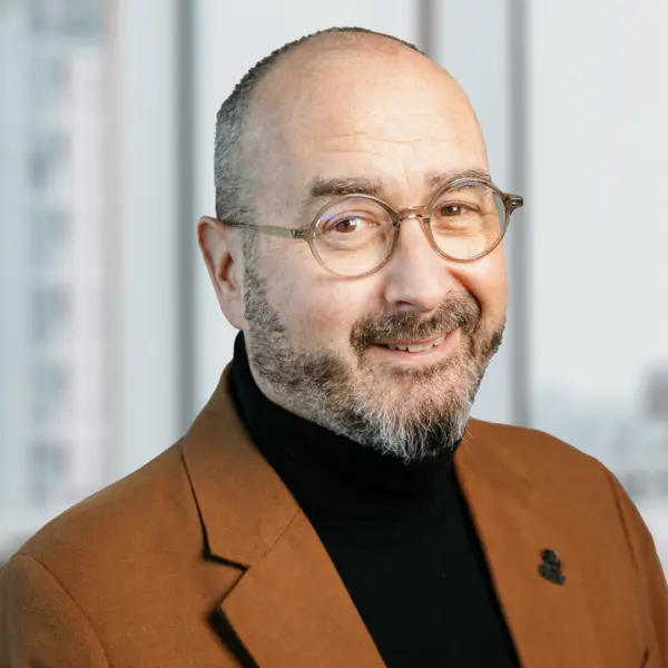 Portrait de Rob Taylor, souriant et portant une veste de costume marron.