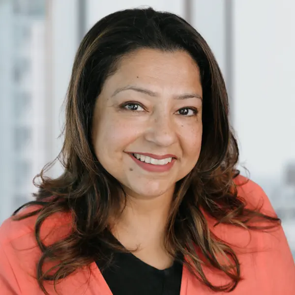 Portrait de Sumeeta Kohli, souriant et portant un chemisier noir.