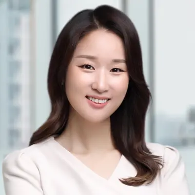 Portrait de Jennifer, souriante et vêtue d'un chemisier blanc.