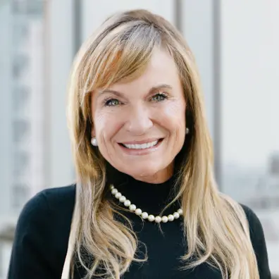 Portrait de Ruth-Ann, souriante, portant un collier de perles et un haut noir.