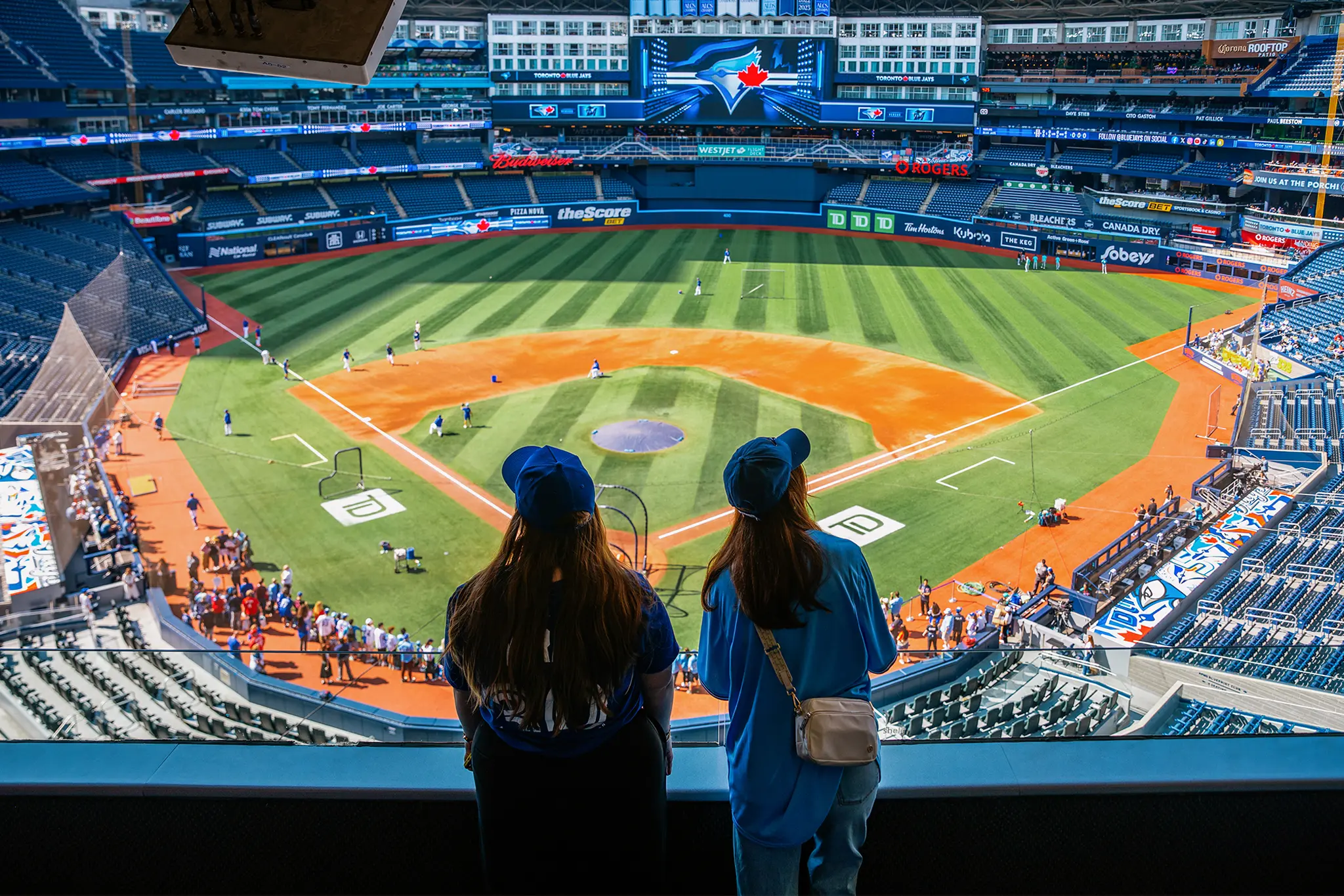 Two people watching a baseball game from the stands of a stadium.