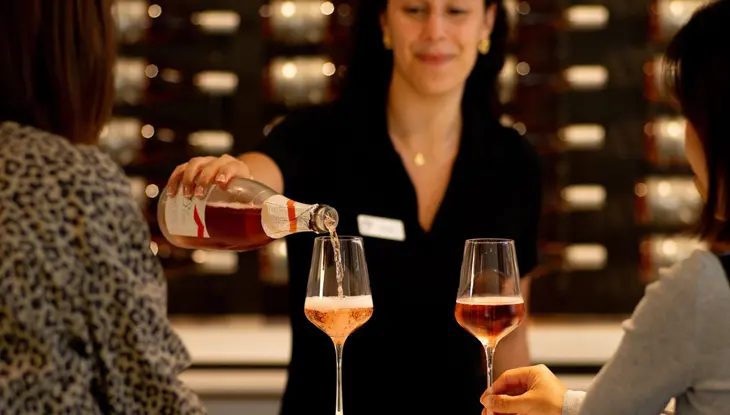 Deux femmes assises au bar de dégustation de la 13th Street Winery, tandis qu’une serveuse verse du rosé dans l’un de leurs verres.