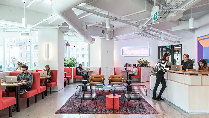 Espacio de coworking moderno con zonas de estar y recepción.