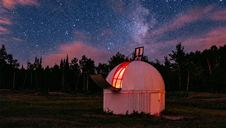 A small observatory dome glowing under a star-filled night sky.