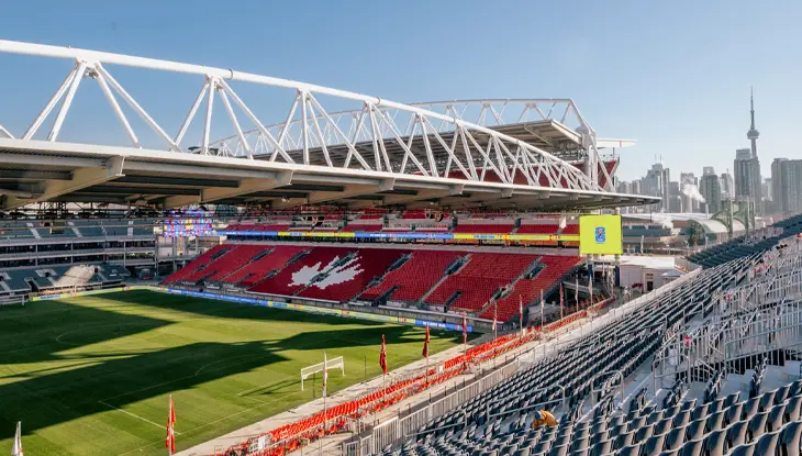 Interior of the Toronto Stadium with red seats and Toronto’s skyline, including the CN Tower, viewed from the stands.