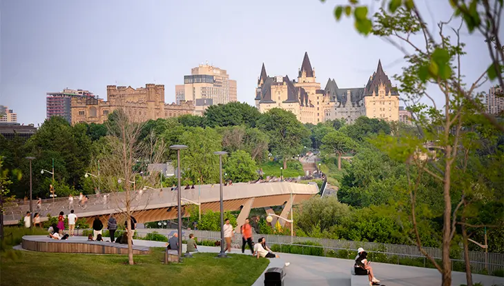Parque con senderos para caminar y edificios de la ciudad al fondo.