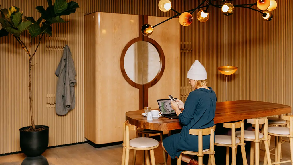 Une personne travaillant à un bureau dans une pièce lambrissée dotée d’un éclairage moderne.