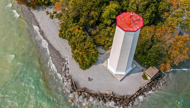 Vue plongeante d’un grand phare hexagonal au toit rouge vif.