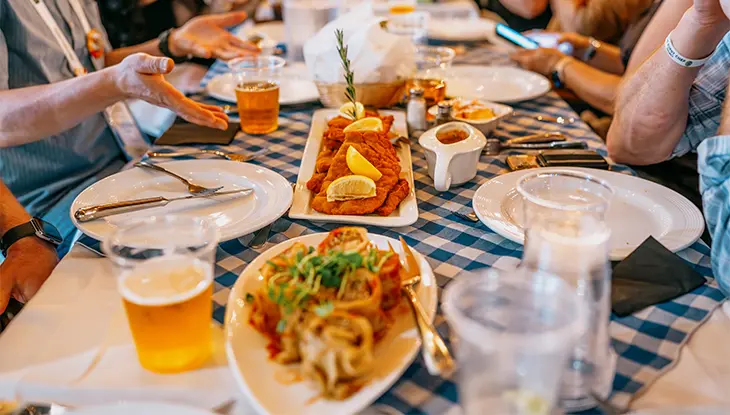 祭りの食事では、市松模様のテーブルにシュニッツェル、パスタ、ビールなどが並べられる。