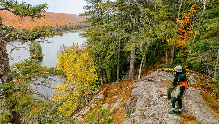 Randonneurs admirant et pointant le lac Oxtongue et la forêt d’automne dans le parc Algonquin.