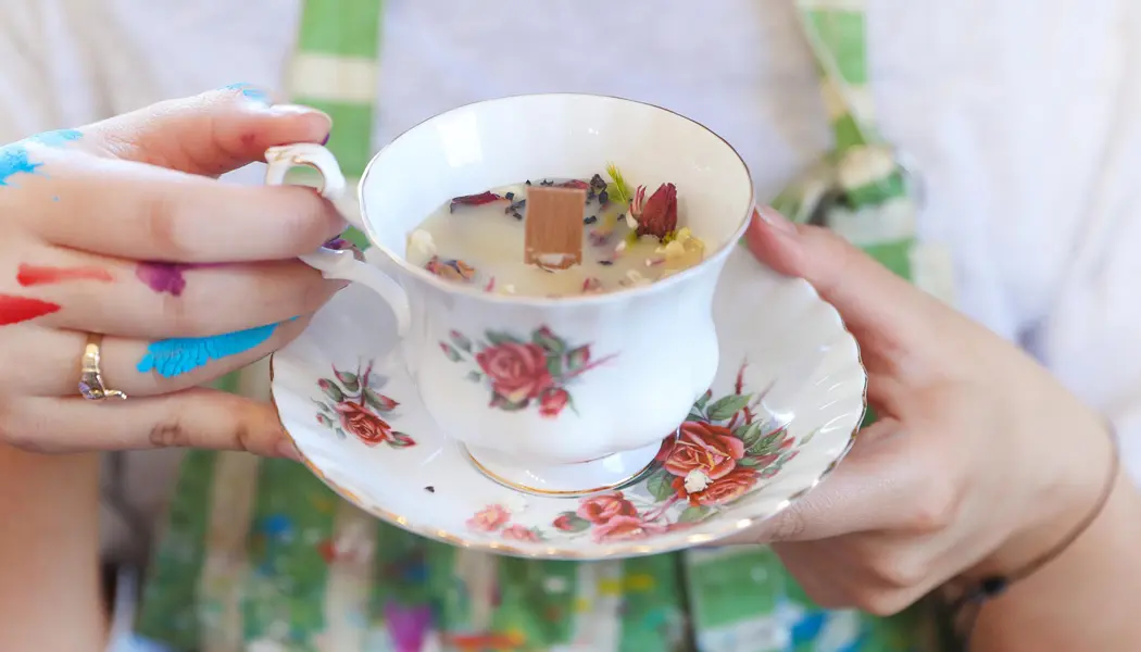 Gros plan sur un artiste, les mains couvertes de peinture, faisant une pause pour savourer une tasse de thé.
